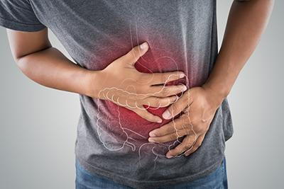 Person holding their stomach towards the left, with a diagram of digestive system above it